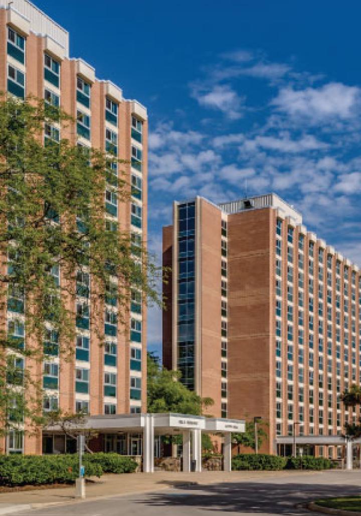 Red brick multi-story buildings under a blue sky with clouds.