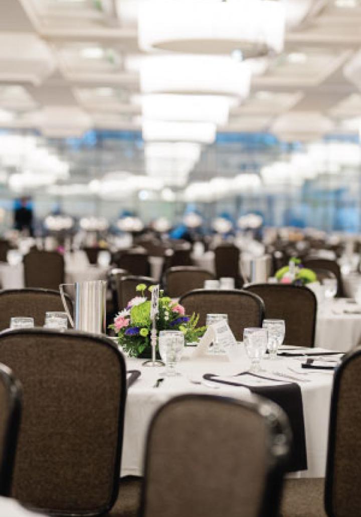 Big Ten rooms in Kellogg Hotel with round tables covered in white tablecloths, floral centerpieces, and arranged glasses.