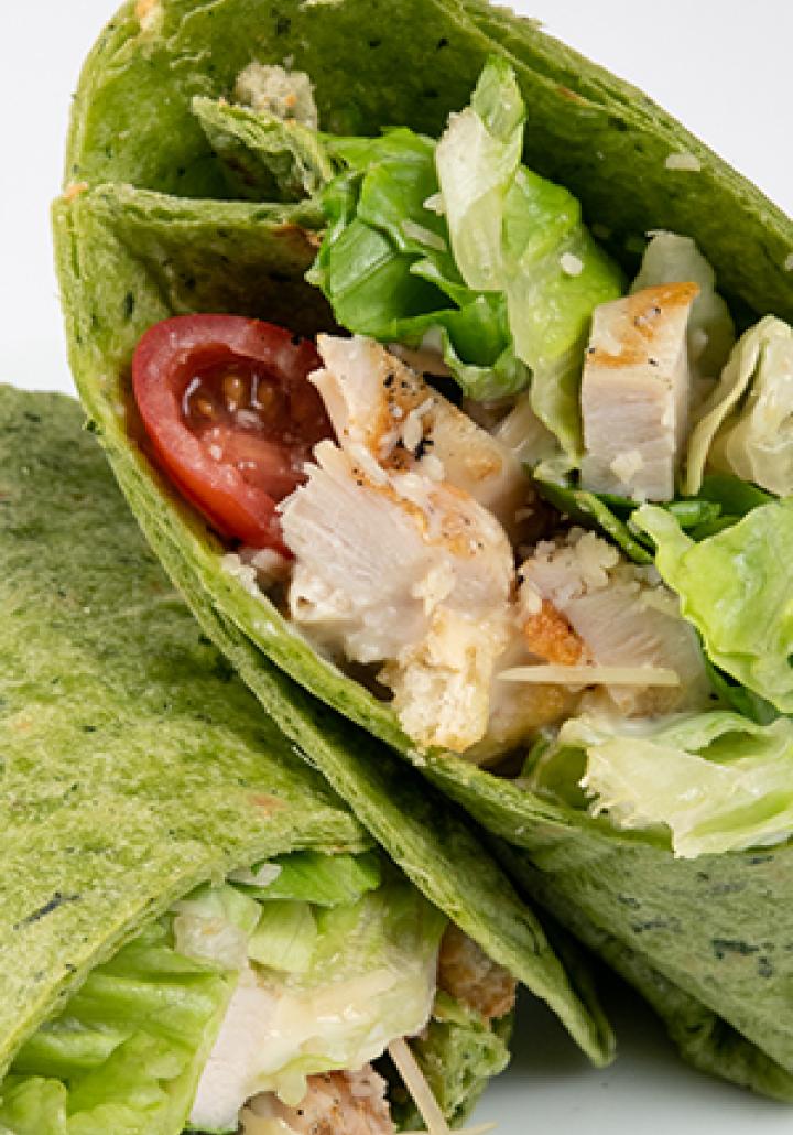 A chicken wrap with lettuce and tomato cut in half